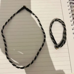 Svart och vit flätat tennhalsband och tenn armband - Snyggt set med ett flätat tennhalsband och matchande tenn armband i svart och vitt. Perfekt för att ge en stilren touch till din outfit. Båda smyckena har en enkel design. Båda för 250.