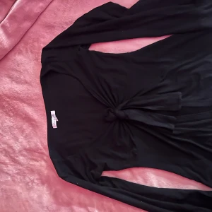 Svart långärmad topp från Design by si - Snygg svart långärmad topp från Design by si med knytdetalj framtill. Säljer pga att den inte kommer till användning längre. Stl  XS-S💕💕