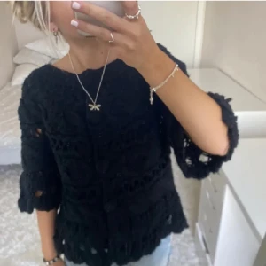 Svart stickad tröja - Säljer en svart stickad kofta med trekvartsärm och vackra virkade detaljer. Super fint skick💕