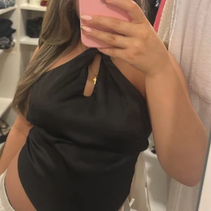 Svart halterneck topp från Gina Tricot - Snygg svart halterneck topp från Gina Tricot med knytning i nacken och öppen rygg. Perfekt för en kväll ute eller en somrig dag. Toppen har en elegant och stilren design.