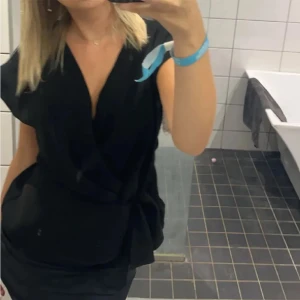 Svart omlottopp - Snygg svart omlottopp med v-ringning och korta ärmar. Perfekt för en stilren look, lätt att matcha med både jeans och kjol. Andvänd en gång storlek xs men passar passar xs/s🩷kan även byta mot en likadan i s/m