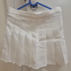 Vit plisserad kjol med undershorts XS/S - Kort vit plisserad kjol. Helt ny, aldrig använd. Kjolen är har dragkedja vid sidan. Storlek mellan XS och S, men lutar mer åt XS hållet. 