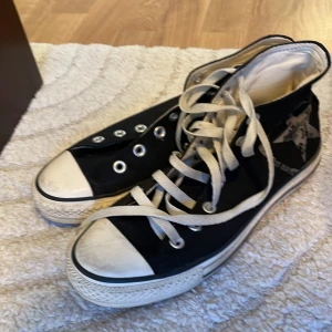 Svarta Converse All Star sneakers - Klassiska svarta Converse All Star sneakers med hög modell och vita snören. Skorna har stjärnloggan på sidan och en vit tåhätta. Knappt använda men högra skon saknar snöre