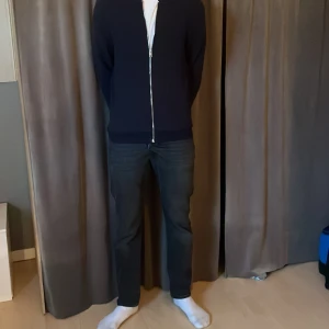 Svarta jeans from jack&jones  - Snygga svarta jeansbyxor med en klassisk straight passform. De har en midwaist design och är perfekta för en stilren look. Byxorna har en dragkedja och knappar framtill.