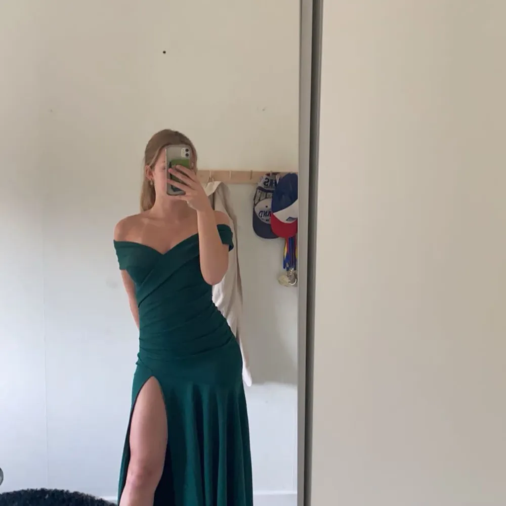 Elegant grön långklänning med offshoulder-design och en stilfull slits. Perfekt för speciella tillfällen.. Mekot.