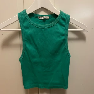 Grön ribbad linnetopp från Zara - Snygg grön ribbad linnetopp från Zara. Perfekt för varma dagar med sin ärmlösa design och bekväma passform. Tillverkad i ett mjukt material som ger en skön känsla mot huden.