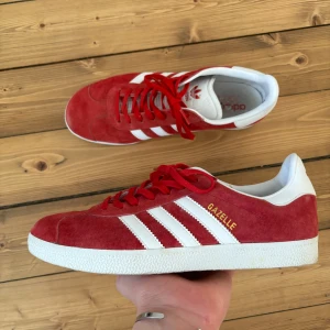 Röda Adidas Gazelle sneakers - Säljer ett par snygga röda Adidas Gazelle sneakers i mocka som inte kommer till användning. Skorna är bara använda några gånger. Skorna är i väldigt bra skick och perfekta för både vardag och fest. Finns inga skador eller liknande. Storlek 42⅔.
