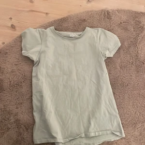 Grön t-shirt från 157 - Säljer en enkel och stilren grön t-shirt från 157. Den är tillverkad i bomull med en liten andel elastan för extra komfort. Perfekt för vardagsbruk! 15kr + frakt 