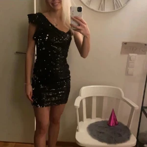 Svart glittrig klänning - Snygg svart klänning med paljetter och en axelbandslös design. Perfekt för festliga tillfällen. Köpt på plock