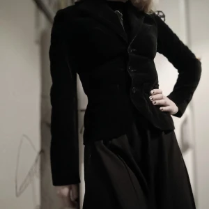 Svart sammet kavaj - Elegant svart kavaj i sammet med knappar framtill. Den har en figurnära passform och långa ärmar, perfekt för en stilren look. Passar bra till både formella och avslappnade tillfällen.