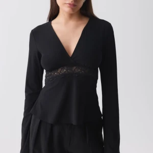 Svart långärmad topp med spetsdetalj - Elegant svart topp med v-ringning och spetsdetalj under bysten. Helt oanvänd, har precis köpt den💕