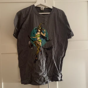 Grå t-shirt med häxmotiv från Gildan - Säljer en grå/brun ish t-shirt från Gildan med ett supercoolt häxmotiv i grönt och svart. Köpt på second hand🖤