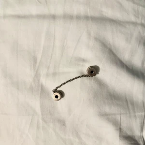 Silver säkerhetskedja från Pandora - Elegant säkerhetskedja i silver från Pandora. Kedjan har två stoppare med detaljerade mönster och är perfekt för att säkra dina berlocker på armbandet. En stilren och praktisk accessoar för ditt smyckesamling.