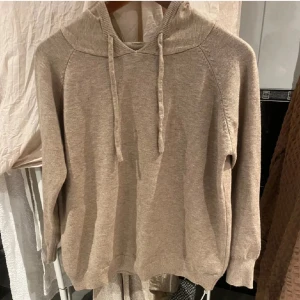 Beige stickad hoodie - Mysig beige stickad hoodie med långa ärmar och justerbar huva. Perfekt för kyliga dagar.