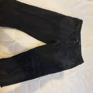 Svarta jeans från Jack & Jones - Säljer ett par svarta jeans från Jack & Jones i modellen Loose/Chris. De har en avslappnad passform och är perfekta för en casual look. Jeansen har klassisk design med dragkedja och knappar. Perfekt skick knappt använda 32/32