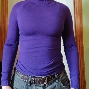 Lila polotröja - Säljer en stilren lila polotröja med lång ärm. Tröjan har en tight passform och är perfekt för kyligare dagar. Den är enkel att matcha med olika outfits och ger en snygg siluett.