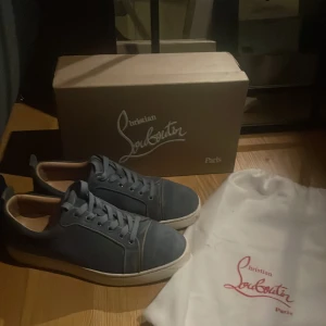 Blå sneakers från Christian Louboutin - Snygga blå sneakers från Christian Louboutin med den ikoniska röda sulan. Skorna har snörning och kommer med originalförpackning och dustbag. Perfekta för den stilmedvetna! Hör av er vid frågor och funderingar