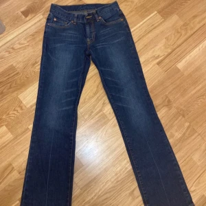 Lowaist jeans från East West bootcut - Snygga mörkblå jeans från East West med klassisk femficksdesign och kontrastsömmar. De har en bootcut/rak passform och är perfekta för en avslappnad stil. Jeansen har en knappgylf och bälteshällor. Den är fin som både modern och vintage. Passar tyvärr ej på mig.