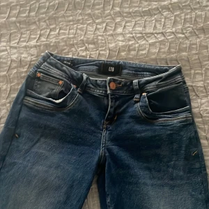 Blå jeans från LTB - Snygga blå jeans från LTB med klassisk femficksdesign och knappgylf. Jeansen har en bootcut passform och är perfekta för en avslappnad stil. De har en mörk tvätt med lätt slitna detaljer för en trendig look. Jeansen är ursprungligen i storlek 29/34 men insydda och uppsydda  så de passar mig som är 165 cm lång! Skulle säga att midjan är storlek 28! Jeansen är i mycket fint skick 