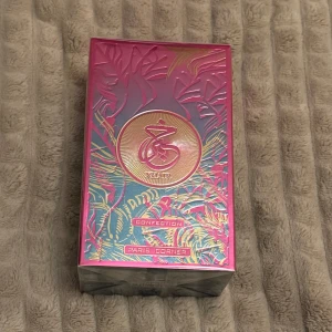 Khair Confection EdP - Upptäck Khair Confection EdP  från Paris Corner. Denna parfym kommer i en elegant rosa och guld förpackning med ett exotiskt mönster. Flaskan innehåller 100 ml av en doft som lovar att förföra dina sinnen. Perfekt för den som söker en unik och lyxig doftupplevelse. Den är inspirerad av Kayali Vanilla Candy Rock Sugar