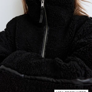 Svart teddyjacka med dragkedja - Mysig svart teddyjacka med dragkedja framtill. Jackan har en oversized passform och långa ärmar, perfekt för kyligare dagar. Den fluffiga texturen ger en trendig look. Nypris 550