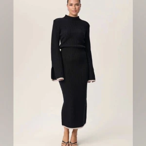 Adoore klänning - Elegant svart ribbad klänning med lång ärm och hög hals. Klänningen har en figurnära passform och slitsdetaljer vid ärmsluten. Perfekt för en stilren look. Helt slutsåld på hemsidan! Pris kan alltid diskuteras, men helt ny, bara använd 1 gång😝 köptes för 1695 kr