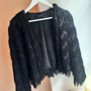 Svart tunn jacka med fransar - Tunn svart jacka/kofta med fransar. Storlek M men passar främst S.