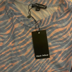 Mönstrad långärmad tröja från Black Colour - Säljer en så fin långärmad mesh topp från Black Colour. Den har ett unikt zebramönster i lila och rosa som verkligen sticker ut. Perfekt för både vardag och fest! Tröjan är ny med lappar och har en skön passform💜