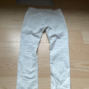 dondup - Säljer ett par vita dondup jeans i nyskick. De har en klassisk femficksdesign och en liten svart detalj vid fickan. Perfekta för både vardag och fest!