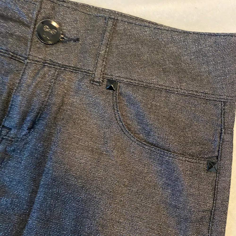 En glittrig miniskirt som är vintage i grå färg och är i jeans material med detaljer runt fickorna. Kjolar.