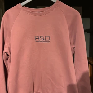 Rosa sweatshirt från Peak Performance - Säljer en snygg  sweatshirt från Peak Performance med broderad logga på både fram- och baksidan. Tröjan har långa ärmar och en bekväm passform. Perfekt för en avslappnad stil.