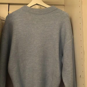 Ljusblå stickad tröja - Mysig ljusblå stickad tröja med långa ärmar och ribbade kanter. Perfekt för kyliga dagar och ger en stilren look. Passar bra till både jeans och kjol.