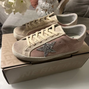 Rosa sneakers med glittrig stjärna - Riktigt snygga rosa sneakers med en glittrig stjärna på sidan. Skorna har beige snörning och en bekväm sula. Perfekta för att ge en touch av glitter till din outfit.|Skick: 9/10| St:37. Kommer med dustbag|vykort från Golden goose samt box. Dma för mer info🤙 