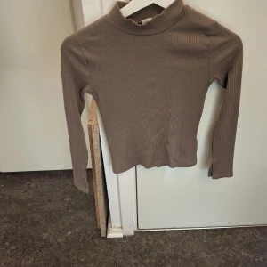 Brun ribbad polotröja. Skriv om ni vill ha en brun kjol till. Det är ett sett - Säljer en stilren brun ribbad polotröja med långa ärmar. Perfekt för kyligare dagar och enkel att matcha med olika outfits. Ett måste i garderoben för den som gillar klassiska plagg.
