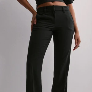 Svarta kostymbyxor - Snygga svarta kostymbyxor med låg midja och rak passform. Byxorna har en klassisk design med dragkedja. Perfekta för en stilren look. Helt som nya. Eftersom de är för stora har jag inte kunnat använda de. De är även vikta i bilderna jag tagit för att de ska passa.💕nypris 399kr 