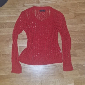 Röd stickad tröja från STOCKH LM(?) - Säljer en snygg röd stickad tröja Tröjan har en v-ringad design och långa ärmar. Den är i en härlig röd färg som ger en pop av färg till din garderob. Passar bra till både jeans och kjol.