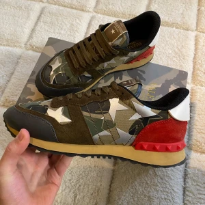 Valentino Rockrunner - Ett par eftertraktade Valentino rockrunners i Cammofärg/grön med röda taggar. Super bra skick, nästan nya. Bortsätt från en blå plutt som saknas( 4de bilden ). Storlek 44 passar även 43. Nypris på dessa ligger på 7000kr. Allt og. För mer info fråga🤗//mvh