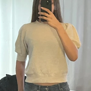 Beige stickad tröja från Vero Moda  - Säljer en stilren beige stickad tröja från Vero Moda. Tröjan har korta ärmar med en lätt puff och ribbade kanter vid ärmslut och nederkant. Säljer då den inte kommer till användning, endast använd 1 gång! Köpte för ca 300-400kr och säljer för 150kr. Perfekt för en avslappnad look. Hör av dig vid intresse! 😊