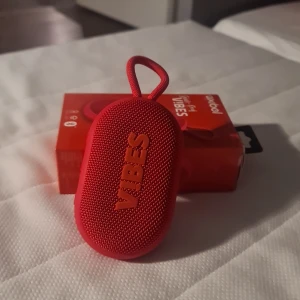 Röd högtalare med förpackning och laddare.  - Röd högtalare med bra ljud och handtag. Skönt att lyssna på hög musik ute i i alla årstider.   