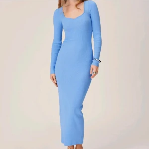 Ljusblå ribbad långklänning - Snygg ljusblå långklänning med ribbad struktur och långärmad design. Klänningen har en v-ringad halslinje som ger en elegant touch. Perfekt för en stilren look.