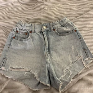 Ljusa jeansshorts från Zara - Snygga ljusa jeansshorts från Zara med slitna detaljer och råa kanter. Perfekta för en avslappnad stil. De har en klassisk femficksdesign och knappgylf.