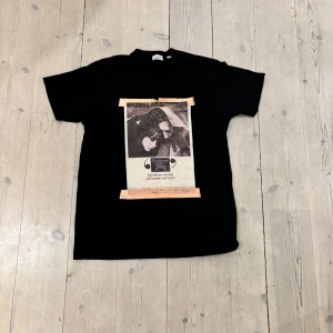Svart t-shirt med tryck från Burberry - Snygg svart t-shirt från Burberry med ett vintage-inspirerat tryck på framsidan. Trycket föreställer ett par i en konstnärlig stil med textdetaljer. Perfekt för dig som gillar en stilren men unik look.tyvärr har trycket lossnat lite men det är inget som märks när man har på den.priset är diskuterbart!
