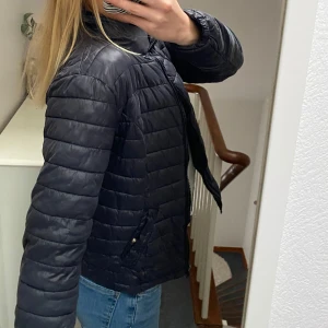 Svart pufferjacka - Säljer en svart pufferjacka med dragkedja och hög krage. Jackan har en quiltad design och långa ärmar, perfekt för kyligare dagar. Den är både stilren och praktisk med fickor på sidorna.storlek M men passar mig som änvänder xs s!!