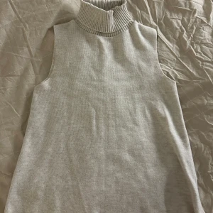 Beige ärmlös polotröja från Zara - Säljer en stilren beige ärmlös polotröja från Zara. Tröjan har en ribbad polokrage och är perfekt för lager-på-lager-stil. Passar utmärkt till både vardag och mer uppklädda tillfällen. Storlek S! 