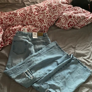 Ljusblå jeans med slitningar från lager 157 - Säljer ett par ljusblå jeans från lager 157 i modellen Boulevard Star. De har coola slitningar på benen och en klassisk femficksdesign. Perfekta för en avslappnad stil. Vida jeans i strl 160 (xs,34)