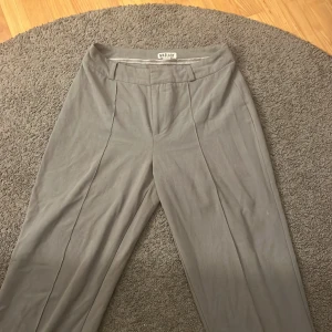 Grå kostymbyxor  - Säljer ett par grå madlaydy byxor i storlek 34/Tall  men är väldigt mjuka o funkar för en stl 36 med!  Säljer då dom inte kommer till användning! 💕 jag har sprättat upp sömnen längst ner för att få dom längre men går att sy upp om man så vill! Se bild!!