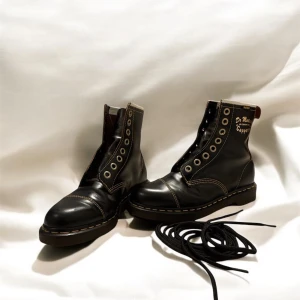 Svarta boots från Dr. Martens - Säljer ett par klassiska svarta Dr. Martens boots i skinn. De har den ikoniska gula sömmen och snörning framtill. Perfekta för både vardag och fest, och de ger en cool touch till vilken outfit som helst. Skorna är i mycket bra skick och redo för nya äventyr!