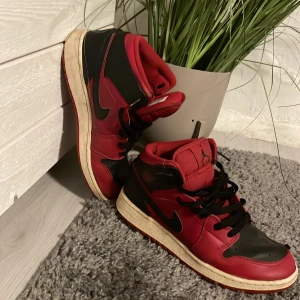 Svart och röd Nike Air Jordans - Säljer ett par klassiska Nike Air Jordans i svart och rött. Skorna har en snygg design med snörning och en bekväm passform. Perfekta för både vardag och träning. De är i bra skick med lite slitage på sulan. Passa på att få tag i dessa ikoniska sneakers!