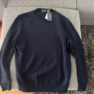 Ralph Lauren stickad tröja - Marinblå stickad sweatshirt från Ralph Lauren, helt oanvänd. Perfekt inför hösten och vintern.