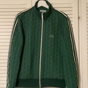 Lacoste Monogram jacka/hoodie - Säljer en snygg grön tröja från Lacoste i storlek M. Just denna modell säljs inte längre, just den gröna med en vit dragkedja går inte att få tag på i butik längre. Använt den fåtal gånger då den är lite för liten för mig. Köpte varan här på Plick så det är endast tröjan jag har och inget kvitto eller liknande. Modellen är små i storlek så ifall du normalt har storlek S passar den perfekt för dig!! Bara och skriva ifall ni vill ha mer bilder eller har några frågor.